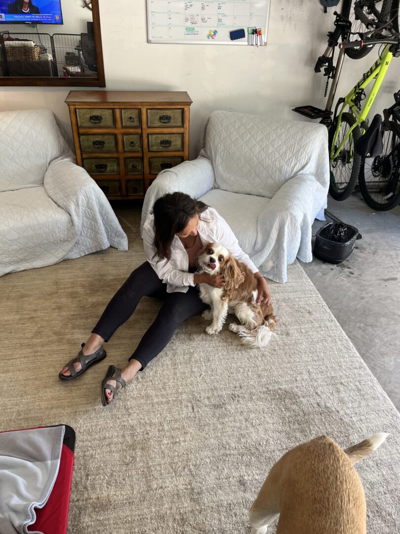 A woman sitting on the floor with her dog.