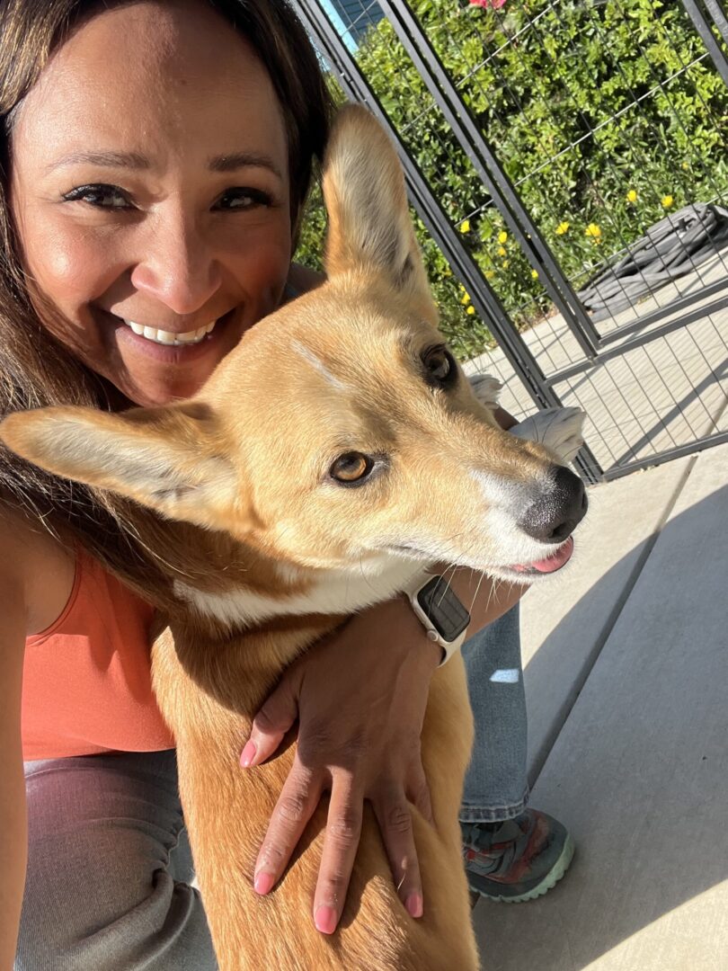 A woman holding onto her dog outside